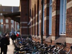 Urban scene featuring a row of parked bicycles along a historic brick wall in daylight.